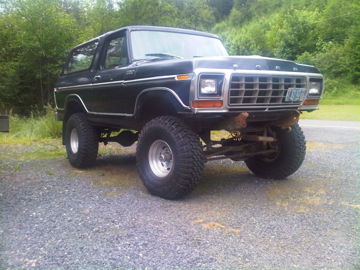 Black lifted Ford Bronco SUV on big mud tires, front 3/4 view on gravel