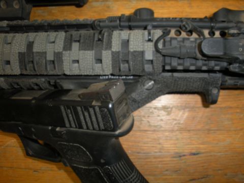 1996 Ford Bronco - A pistol is mounted to the underside of an assault rifle's handguard, which is wrapped in paracord.
