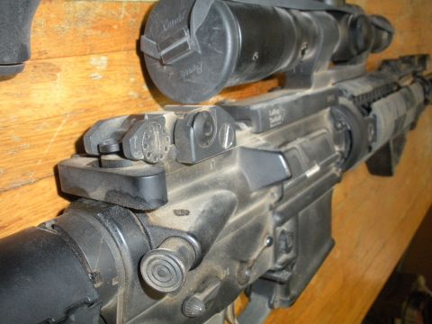 1996 Ford Bronco - This image shows a close-up view of an assault rifle, complete with a mounted scope, against a wooden background.