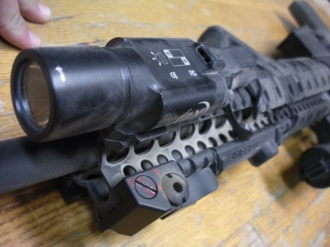 1996 Ford Bronco - A tactical flashlight is mounted to a rifle's handguard, with visible text on the flashlight body.