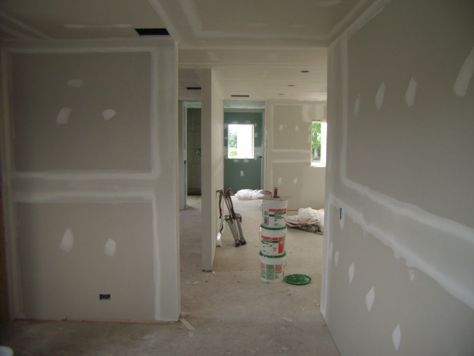 Interior of a house under construction with drywall and buckets of joint compound