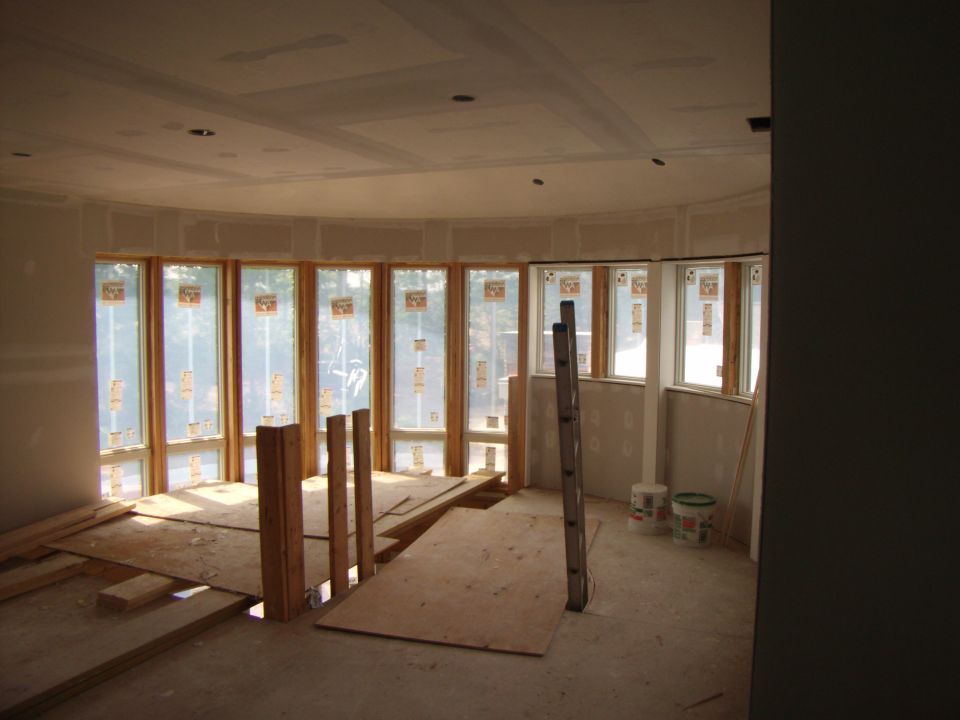 Interior construction with drywall, windows, and lumber on the floor