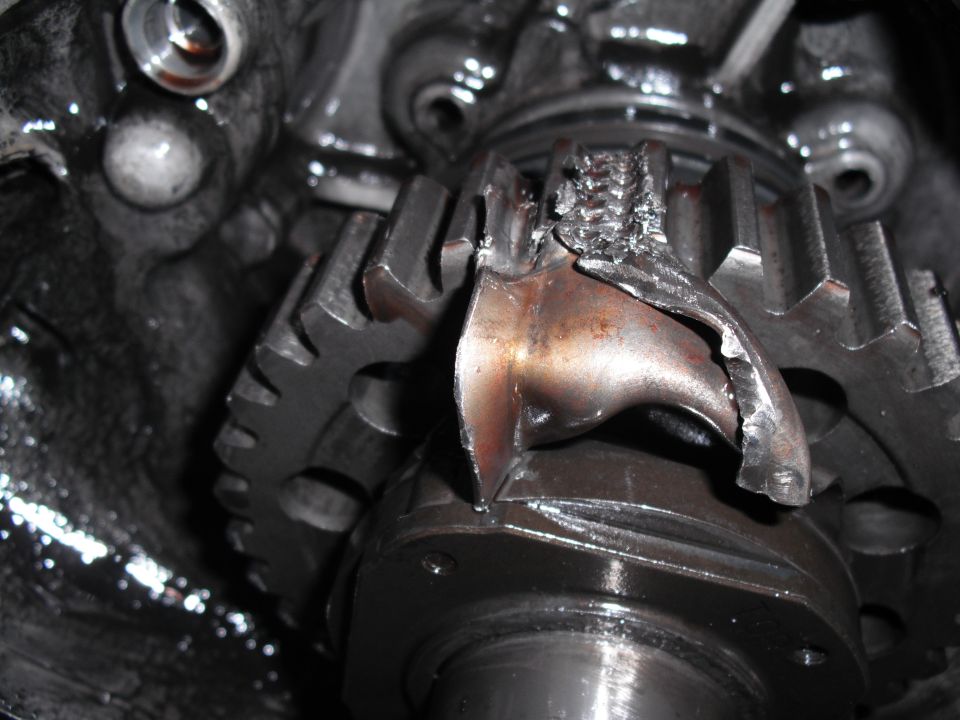Damaged transfer case gears with bent and broken teeth, showing metal fatigue and wear