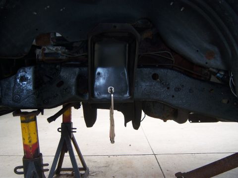 1996 Ford Bronco - Undercarriage of a vehicle supported by jack stands, showing frame and suspension parts during a tear down.