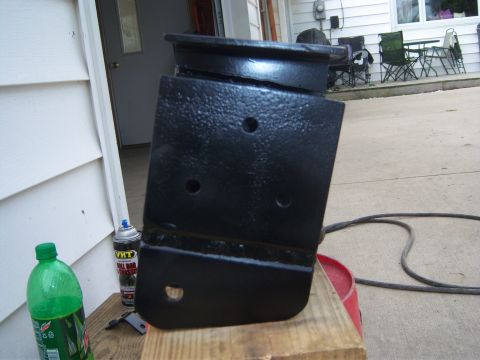 1996 Ford Bronco - A close-up view of a freshly painted metal bracket, likely a vehicle part, resting on a wooden surface.
