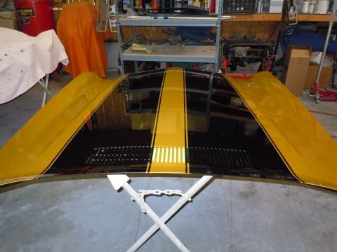 1970 Chevrolet Camaro - A car hood with black and yellow stripes is displayed in a workshop.