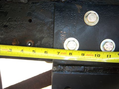 1996 Ford Bronco - A yellow Stanley tape measure is used to measure a section of a vehicle's frame, indicating approximately 8 inches.