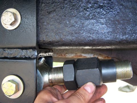 1996 Ford Bronco - Close-up of a vehicle's suspension linkage being adjusted with a large nut.