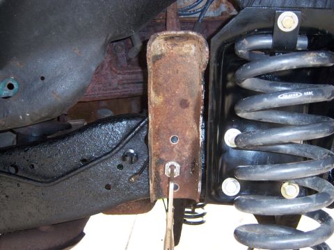 1996 Ford Bronco - Underside close-up of a solid-axle front suspension during a lift or swap, showing a rusty coil spring bucket/shock mount bolted to a fresh…