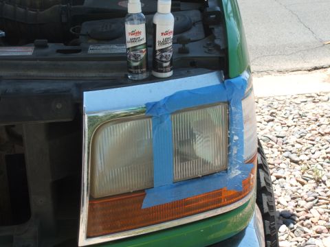 1995 Ford Bronco - Headlight restoration in progress on a green Ford Bronco, with cleaning supplies ready.