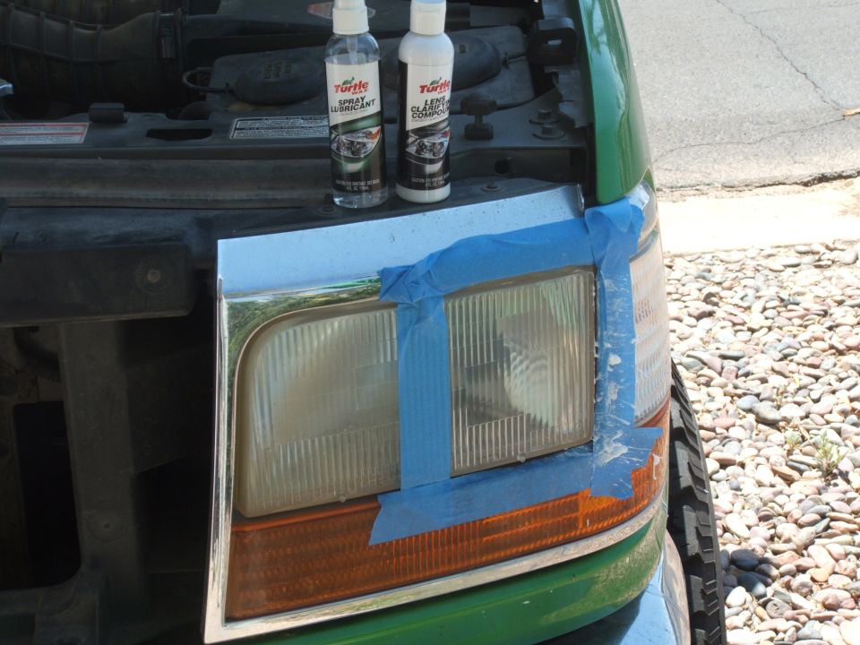 Green Ford Bronco with taped headlight assembly and two Turtle Wax bottles on the hood