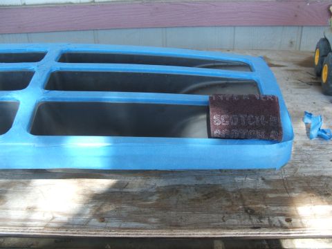 1995 Ford Bronco - Grille taped off for refinishing, with a Scotch-Brite pad resting on it.