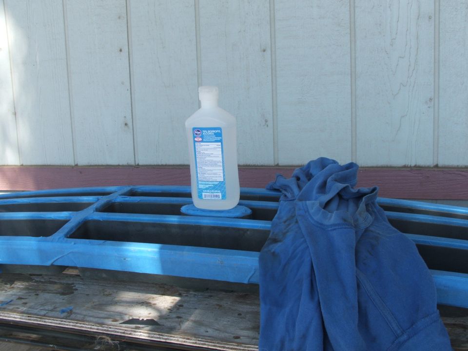 Bottle of rubbing alcohol and a blue t-shirt on top of a blue grille