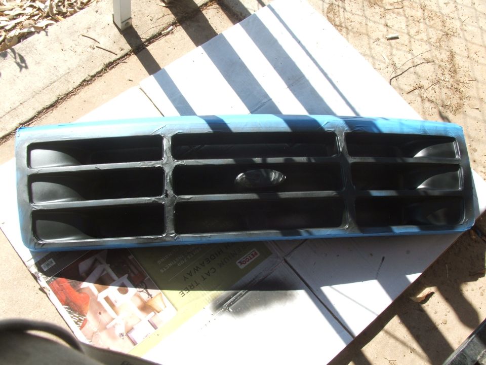 Ford Bronco grille taped off for painting. Oval Ford logo visible in center