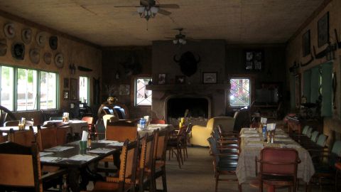 1996 Ford Bronco - A dimly lit dining area features tables set for meals, a large stone fireplace, and decorative hats on the wall.