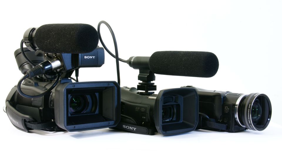 Three black Sony camcorders with microphones and viewfinders arranged on a white surface