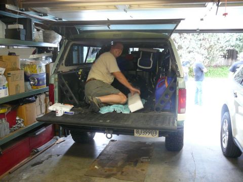 1988 Ford Bronco - Man loading items into the rear of a 1988 Ford Bronco, parked in a garage.