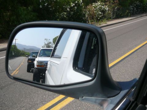 1988 Ford Bronco - Side mirror view shows two trucks driving on a road, one white and one black.