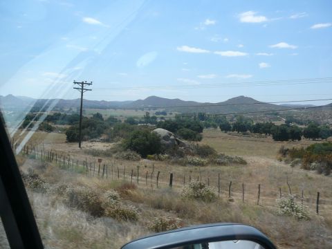 1988 Ford Bronco - A view of a dry, rural landscape with scattered trees and rolling hills under a partly cloudy sky.