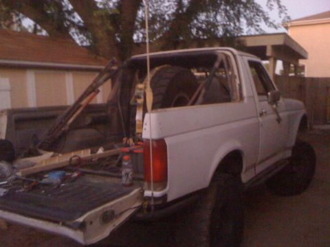 1990 Ford Bronco - This 1990 Ford Bronco features a roll cage and a spare tire mounted in the rear cargo area.