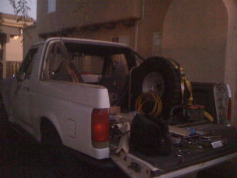 1990 Ford Bronco - White 1990 Ford Bronco with spare tire and various items in the cargo bed.