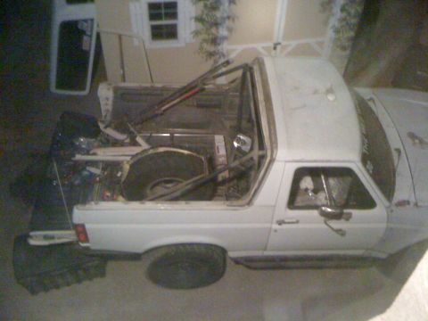 1990 Ford Bronco - This modified Ford Bronco has a roll cage and the removable top is off, showing the interior and spare tire.
