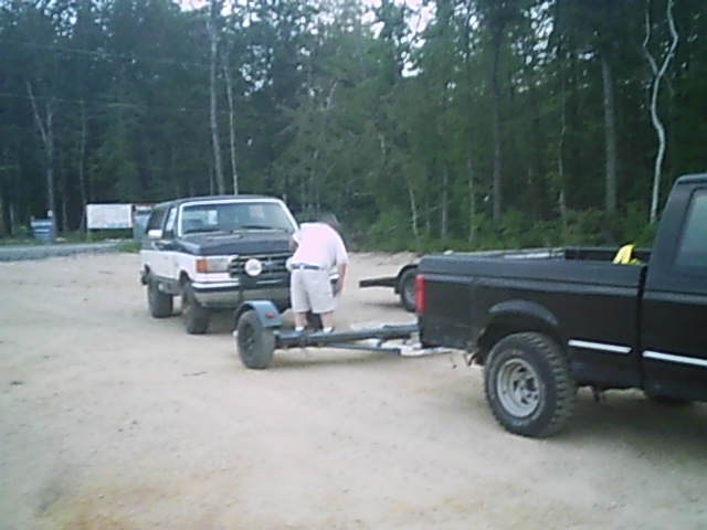 Two-tone SUV hitched to a trailer, with a black pickup truck beside it