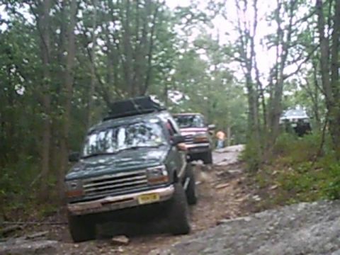 1988 Ford Bronco - Multiple off-road vehicles navigate a challenging path through a dense forest.