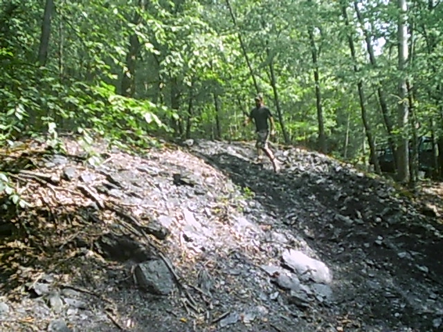 Person running up a rocky, wooded hill. Supermotors logo in corner