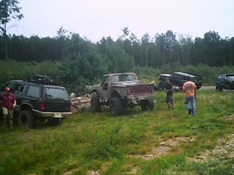 1988 Ford Bronco - A group of off-road vehicles are gathered in a wooded area, suggesting an outdoor adventure or trail ride.
