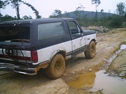 1988 Ford Bronco - This two-tone Ford Bronco navigates a challenging muddy terrain, its off-road capabilities.