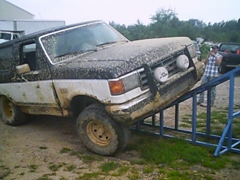 1988 Ford Bronco - This 1987 Ford Bronco is covered in mud and positioned on a blue ramp, suggesting off-road use.