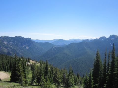 2008 Jeep Wrangler - A scenic view of mountains and forests, with a dirt road winding through the trees.