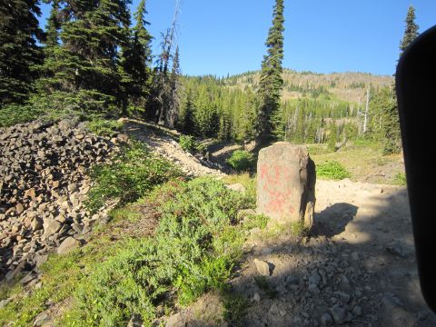 2008 Jeep Wrangler - A stone marker stands on a dirt path surrounded by trees and rocky terrain.