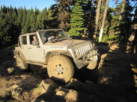 2008 Jeep Wrangler - A Jeep Wrangler navigates a rocky trail surrounded by trees.