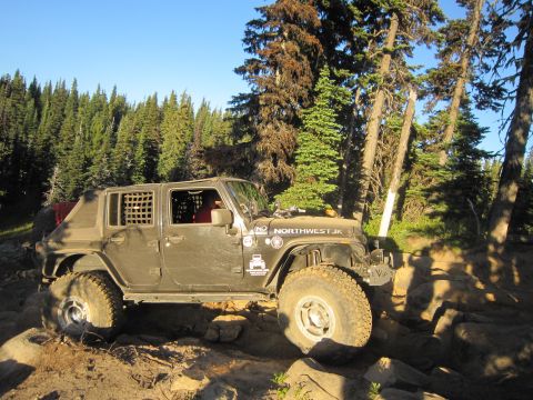 2008 Jeep Wrangler - A modified Jeep Wrangler navigates a challenging, rocky off-road trail under a clear blue sky.