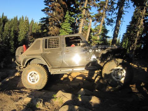 2008 Jeep Wrangler - A black Jeep Wrangler navigates a rocky trail through a forest.