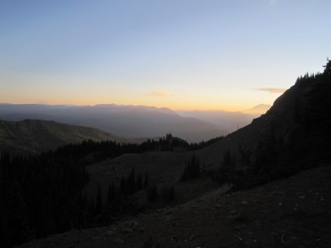 2008 Jeep Wrangler - The sun sets over a vast mountain range, casting long shadows across the forested slopes.