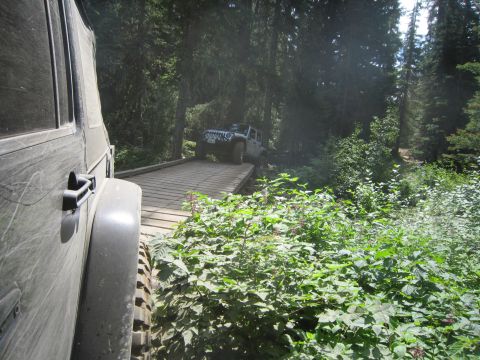 2008 Jeep Wrangler - Two Jeep Wranglers navigate a wooden bridge on a forest trail. The lead vehicle is white, while the foreground vehicle is dark-colored.