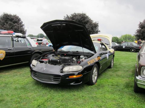 1991 Ford LTD Crown Victoria - Black coupe marked STATE TROOPER with hood raised exposing the engine, displayed on grass among other police cars.
