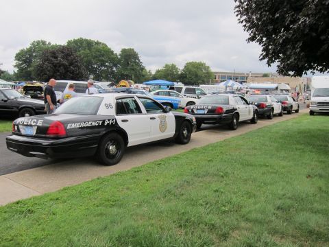 1991 Ford LTD Crown Victoria - Rear three-quarter view of a black-and-white police cruiser numbered 96 marked Emergency 9-1-1 in a lineup of patrol cars.