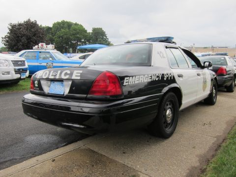 1991 Ford LTD Crown Victoria - Rear three-quarter of a black-and-white police Crown Victoria numbered 12 marked Police and Emergency 9-1-1 with light bar.