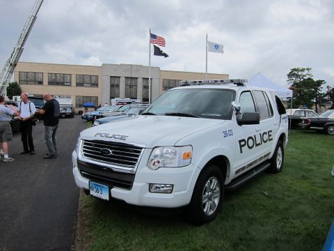 1991 Ford LTD Crown Victoria - Front three-quarter of a white Ford Explorer police SUV numbered 36-03 with push bar, flags and a building in the background.