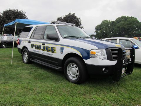 1991 Ford LTD Crown Victoria - white-and-blue Ford Expedition police SUV marked Western New England University with a push bar parked on grass at a show.