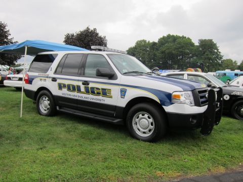1991 Ford LTD Crown Victoria - Profile of a white-and-blue Ford Expedition police SUV marked Western New England University parked on grass at a show.
