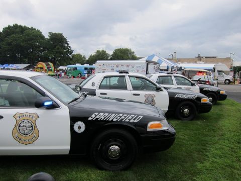 1991 Ford LTD Crown Victoria - row of black-and-white Springfield Police Ford Crown Victoria cruisers with badge decals lines up at an outdoor event.