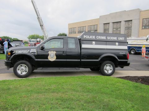 1991 Ford LTD Crown Victoria - Profile view of a black Springfield Police Crime Scene Unit Ford 4x4 pickup with a white-lettered bed cap parked near a building.