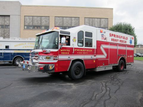 1991 Ford LTD Crown Victoria - Front three-quarter view of a red-and-white Springfield Heavy Rescue fire squad truck parked on pavement near a building.
