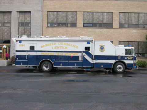 1991 Ford LTD Crown Victoria - Side view of a large blue-and-white Springfield Police Department Mobile Command Center truck parked in front of a building.