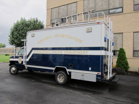 1991 Ford LTD Crown Victoria - Rear three-quarter view of a blue-and-white Springfield Police Department Forensic Investigation box truck parked near a building.